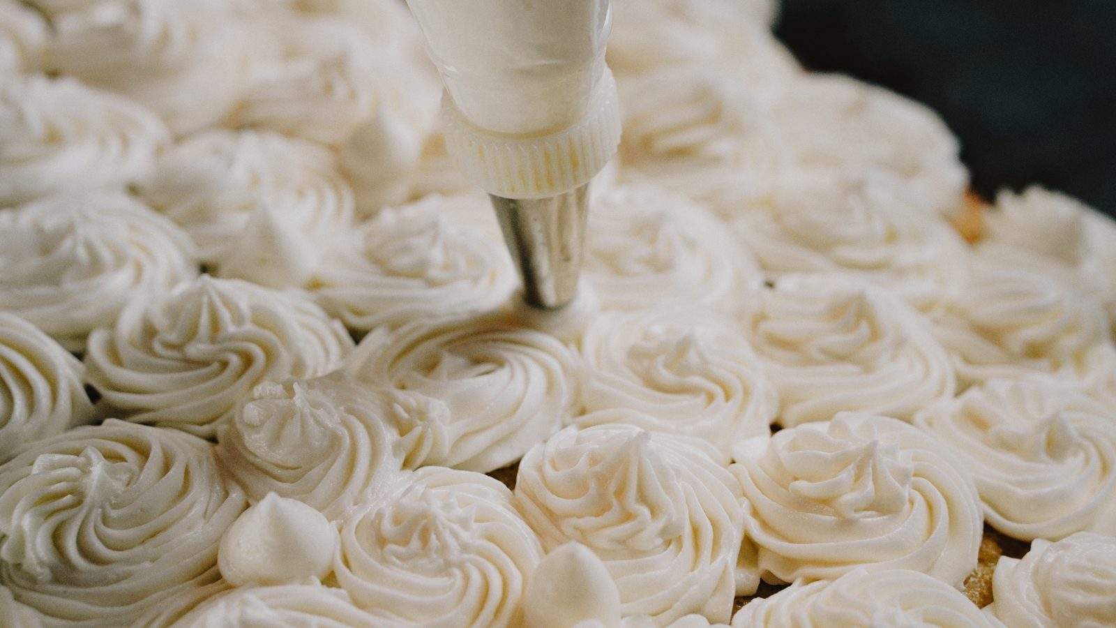 Buttercream rosettes piped by hand across a fresh cake